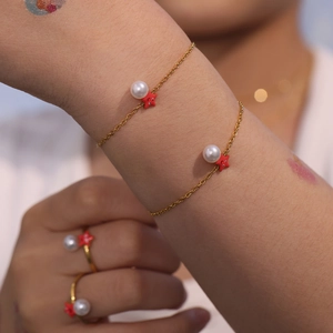 Pulsera dorada con estrella de mar y perla en la muñeca con dijes de estrella y perla blanca