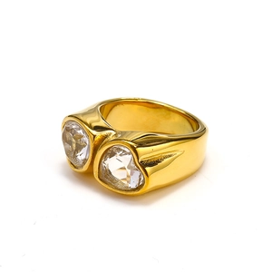 Detail of chunky gold titanium ring featuring two heart-shaped crystal stones and a thick band