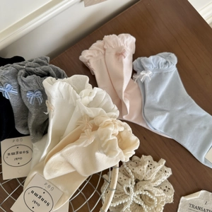 Detail of sweet cotton socks featuring ruffled edges and delicate bow accents in soft colors