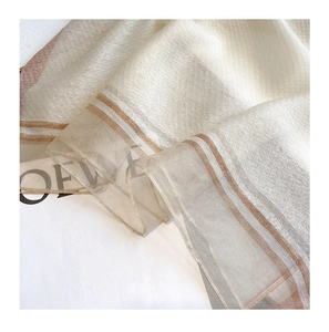 Macro detail of creamy silk-wool scarf with brown striped edges and soft light texture
