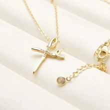 Close-up of gold cross pendant with tiny crystals on a double layer snake chain necklace