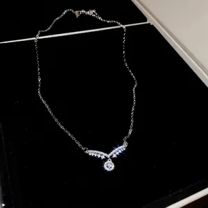 Collier avec pendentif ailes en argent et zircons dans un écrin de bijoux en velours noir