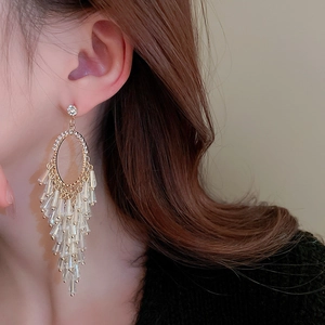 Macro view of gold crystal fringe earrings featuring layered tassels and diamond studs