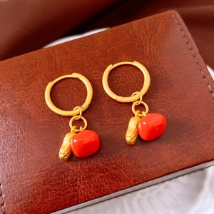 Detailed macro of gold persimmon and peanut pendants on elegant leverback hoop earrings