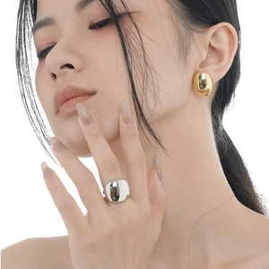 Set di lusso con orecchino a ciottolo dorato e anello in argento lucido indossato dal modello