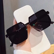 Close-up of black oversized geometric sunglasses with thick frames and dark lenses