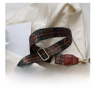 Detailed view of ethnic style woven shoulder strap with gold metal buckles and brown leather