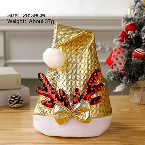 Golden sequin Christmas hat with red antlers and white pom-pom on wooden table