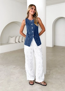 Close-up of blue denim vest and white floral lace wide-leg trousers on a female model