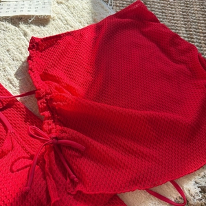 Dettaglio della trama a nido d'ape rossa del bikini con laccetti regolabili sul fianco