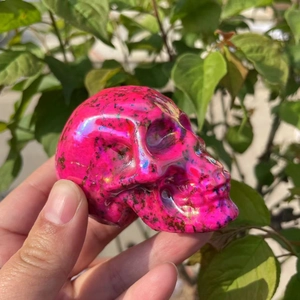Handheld 7cm aura pink crystal skull carving with iridescent metallic finish and spots