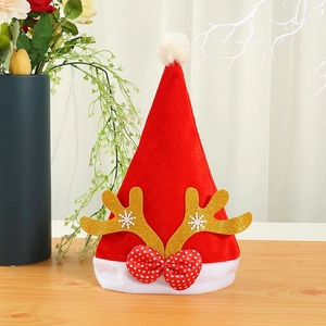 Red velvet Christmas hat with gold antlers and snowflake pattern on a wooden surface