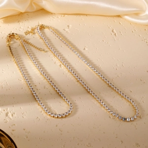 Elegant gold tennis necklace set with sparkling round cubic zirconia on stone background