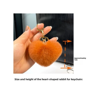 Close-up of 7cm orange faux rabbit fur heart keychain with gold metal clasp on a bag