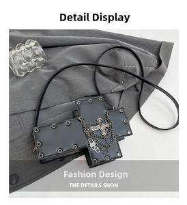 Gothic cross-shaped crossbody bag with metal rings, chains and skull charms on matte leather