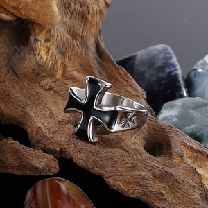 Macro shot of silver stainless steel ring with black enamel cross on wood texture