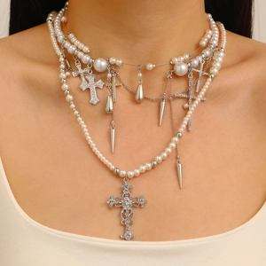 Close-up of layered silver cross necklace with pearls and crystal spikes on a model