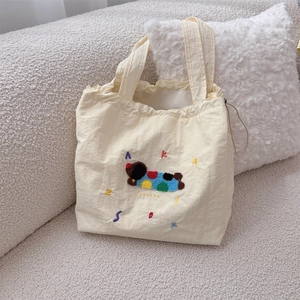 Detail of cute towel embroidery dog pattern on cream canvas tote bag with drawstring closure