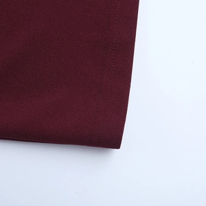 Détail d'une robe bordeaux montrant des coutures à double aiguille et un tissu tissé fin