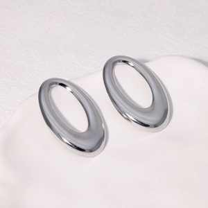 Minimalist silver oval hoop earrings made of polished stainless steel on white ceramic tray