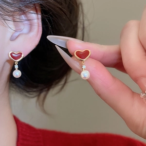 Detail of red heart earring with crystal studs and drop pearl on model