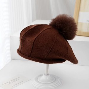 Détail d'un béret en tricot marron avec un grand pompon et une texture douce