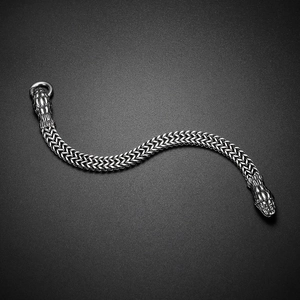 Macro detail of punk style double-row woven chain bracelet with engraved snake heads