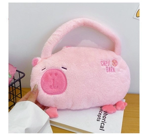 Detailed view of a cute pink plush capybara backpack with CAP/BARA embroidery on wood table