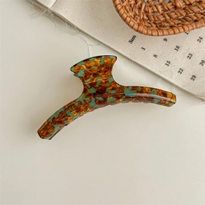 Detail of large acetate hair claw clip with tortoise leopard pattern on beige surface
