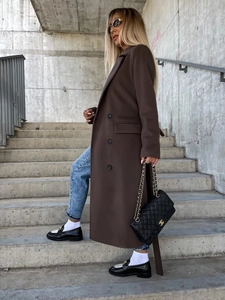 Detail of long dark brown wool coat with lapel collar and buttons on a street model