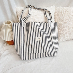 Close-up of black and white striped canvas tote bag with front pocket and text patch