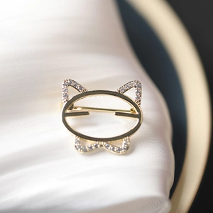 Macro detail of golden cat brooch with rhinestones on white silk texture fabric