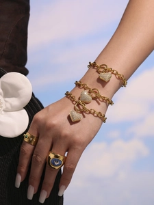 Modella che indossa bracciali dorati con ciondolo a cuore, chiusura a T e pietre di zircone