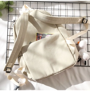 Detail view of adjustable shoulder straps and durable canvas texture on a beige backpack