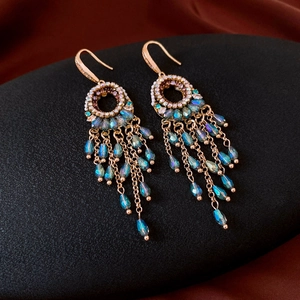 Detail of vintage gold tassel earrings with zircon circles and turquoise waterdrop beads