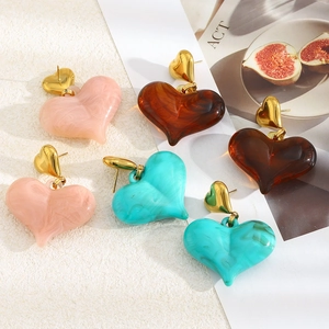 Détail de boucles d'oreilles cœur en acier doré avec résine effet marbre rose et ambre