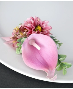 Close-up of pink calla lily boutonniere with daisies and berries for wedding decor