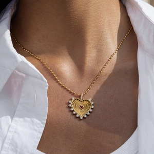 Elegant gold heart pendant necklace with red and white stones on female model