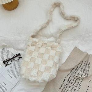 Macro shot of fluffy beige and white checkered plush bucket bag on a minimalist background
