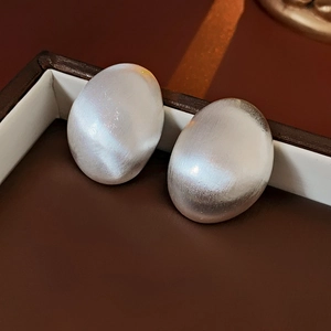 Gros plan de boucles d'oreilles ovales en argent avec texture en métal brossé vintage