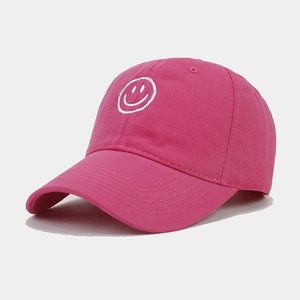 Close-up of white smiling face embroidery on rose pink cotton baseball cap fabric