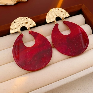 Macro shot of dark red resin drop earrings with gold hammer-textured metal finish