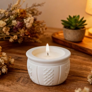 Close-up of a lit relief ceramic scented candle with floral textures in a cozy setting
