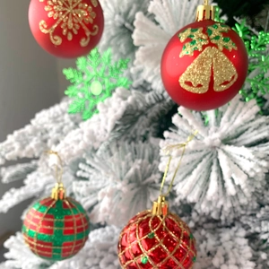 Dettaglio di palline di Natale rosse e verdi con motivi glitter oro sull'albero