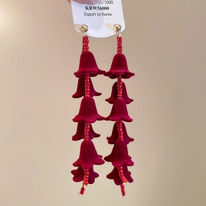 Vue détaillée des boucles d'oreilles à fleurs bordeaux floquées avec pompon à cinq couches