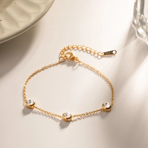 Golden stainless steel bracelet featuring three bezel-set round zircons and extension chain