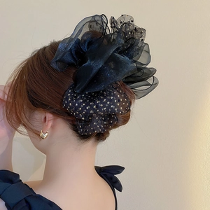 Détail d'un chouchou en organza noir à paillettes dorées sur une coiffure en chignon