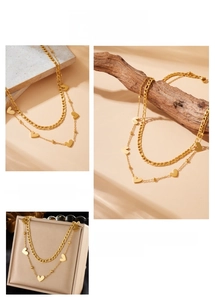 Detail of layered gold stainless steel necklace with flat chain and heart pendants