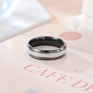 Close-up of black titanium ring with silver frosted texture inlay and polished edges