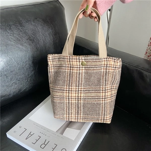 Close-up of retro plaid canvas handbag with textured fabric straps and metal snap button